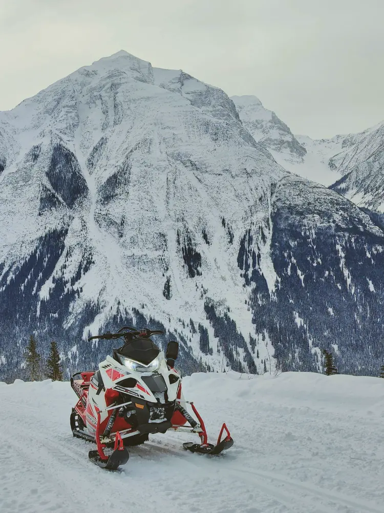 Jani's red and white Yamaha Sidewinder parked in front of a snowy mountain
